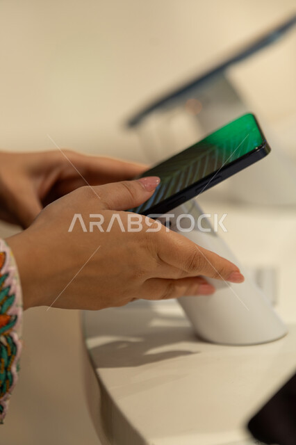امرأة إماراتية تتفحص هاتف ذكي في متجر