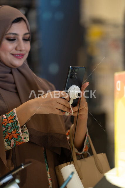 Emirati Woman Using Smartphone in Retail Store
