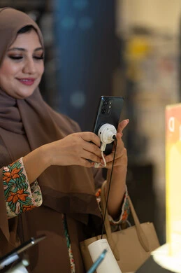 امرأة إماراتية تستخدم هاتف ذكي في متجر