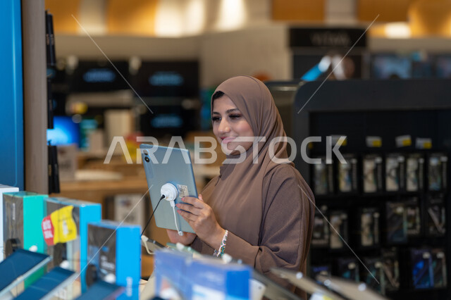 امرأة سعودية تتصفح جهاز لوحي في متجر إلكترونيات
