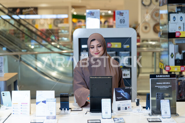 امرأة سعودية تتسوق لشراء هاتف ذكي في متجر إلكترونيات