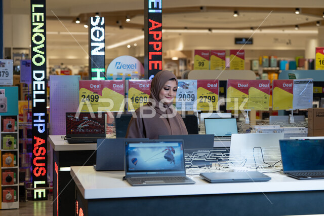Arab Woman in Abaya Browsing Laptops in Electronics Store