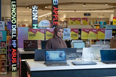 امرأة عربية بالعباءة تتسوق أجهزة لابتوب في متجر إلكترونيات