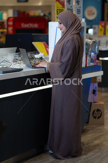 Saudi Woman in Abaya Using Laptop in Electronics Store