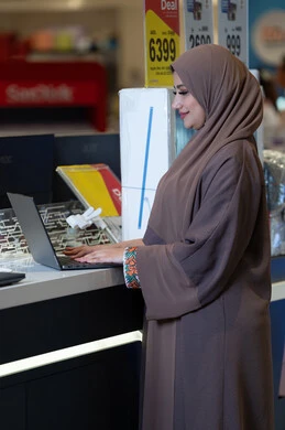 امرأة إماراتية تستخدم لاب توب في متجر إلكترونيات