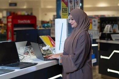 امرأة عربية تستخدم لابتوب في متجر إلكترونيات