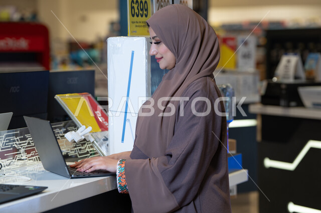 امرأة سعودية تستخدم لابتوب في متجر إلكترونيات