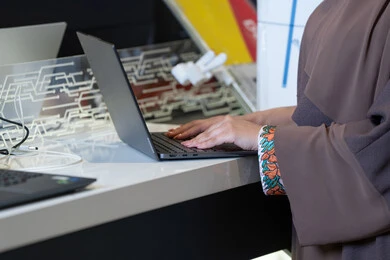 امرأة إماراتية تطبع على الكمبيوتر المحمول بالعباءة