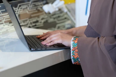 امرأة إماراتية بالعباية تكتب على حاسوب محمول