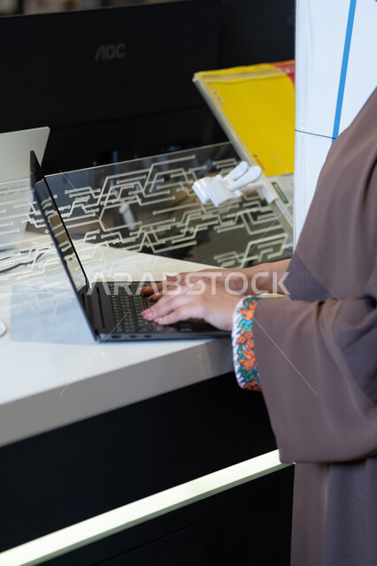 Saudi Woman in Abaya Typing on Laptop at Service Desk