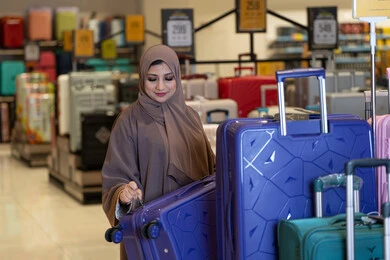امرأة عربية بالعباءة تتسوق لشراء حقائب السفر في المتجر امرأة عربية بالعباءة تتسوق لشراء حقائب السفر في المتجر