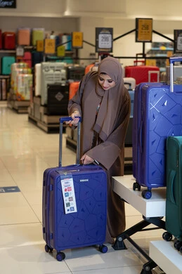 امرأة سعودية تتسوق لشراء حقائب السفر في متجر تجاري