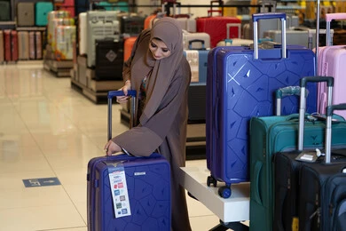 امرأة عربية تتسوق لشراء حقائب السفر في المتجر