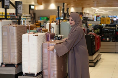 امرأة عربية تتسوق حقائب سفر في متجر تجزئة