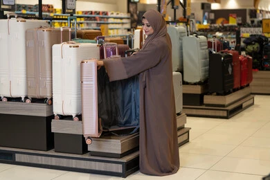 امرأة سعودية تتسوق لشراء حقيبة سفر في متجر