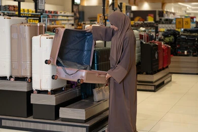 امرأة عربية تتفحص حقيبة سفر في متجر تجزئة