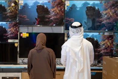 زوج إماراتي يتسوقان لشراء أجهزة تلفزيون في متجر إلكترونيات