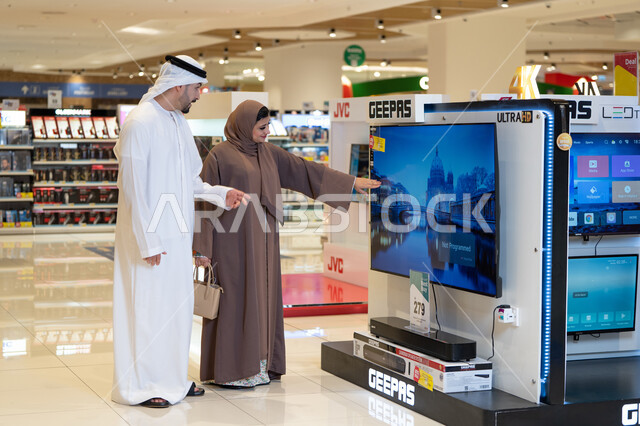 زوجان إماراتيان يتسوقان لشراء تلفزيون في متجر إلكترونيات