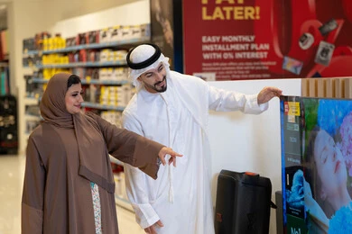 زوجان إماراتيان يتسوقان لشراء تلفزيون في متجر إلكترونيات