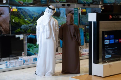 زوج إماراتي يتسوق لشاشات التلفزيون في متجر إلكترونيات