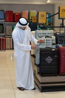 رجل إماراتي يتسوق لشراء حقائب سفر في متجر