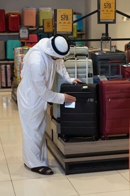 رجل إماراتي بالكندورة يتسوق لشراء حقائب السفر