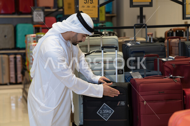 رجل إماراتي يتسوق حقائب السفر في متجر تجاري