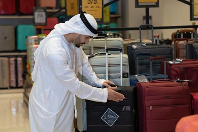 رجل إماراتي يتسوق حقائب السفر في متجر تجاري