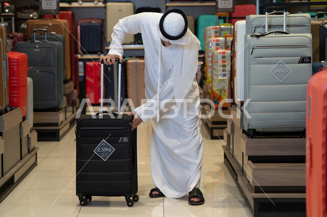 رجل إماراتي يختار حقيبة سفر في متجر حقائب