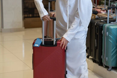 رجل سعودي بالثوب الأبيض يختار حقيبة سفر حمراء