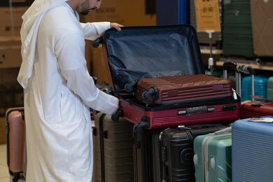 رجل سعودي بالثوب التقليدي يتسوق لشراء حقائب السفر