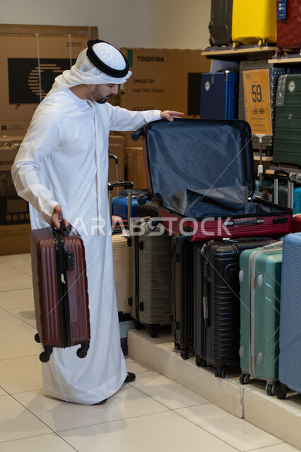 رجل إماراتي يتسوق لشراء حقائب السفر في المتجر