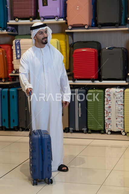 رجل إماراتي يرتدي الكندورة يتسوق في متجر حقائب سفر