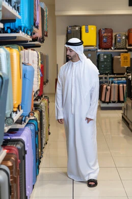 رجل إماراتي يتسوق لشراء حقائب سفر ملونة في متجر