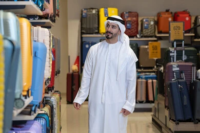 رجل إماراتي يتسوق لشراء حقائب سفر في متجر