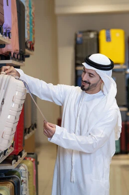 رجل إماراتي يتسوق لشراء حقيبة سفر في المتجر