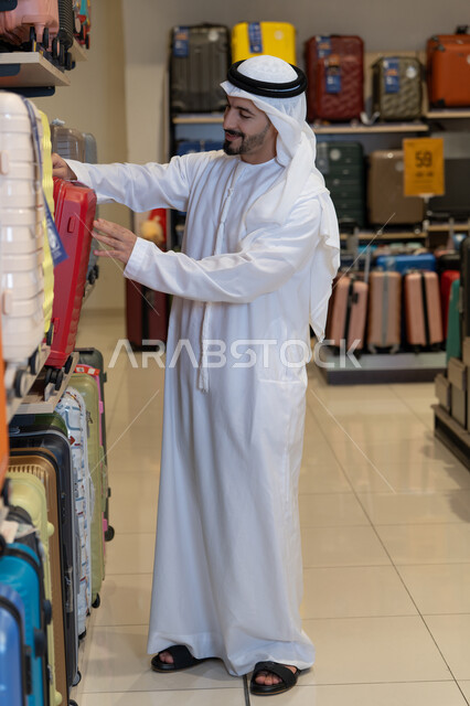 رجل إماراتي يتسوق لشراء حقائب سفر في المتجر