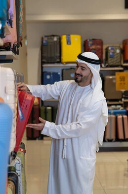 رجل إماراتي يختار حقيبة سفر في متجر حقائب
