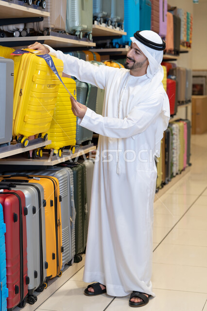 رجل إماراتي يتسوق حقائب سفر في متجر تجاري
