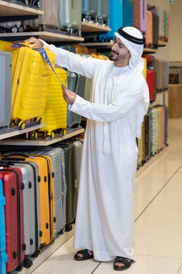 رجل إماراتي يتسوق حقائب سفر في متجر تجاري