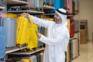 رجل إماراتي يتسوق لشراء حقيبة سفر في المتجر