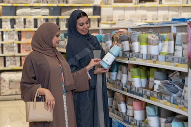 امرأتان عربيتان تتسوقان المنسوجات المنزلية في متجر