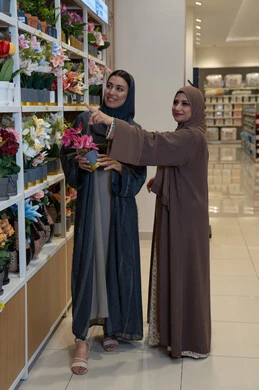 سيدات عربيات بالعباءة يتسوقن الزهور في متجر حديث