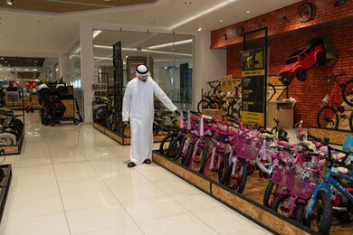 رجل إماراتي باللباس التقليدي في متجر دراجات