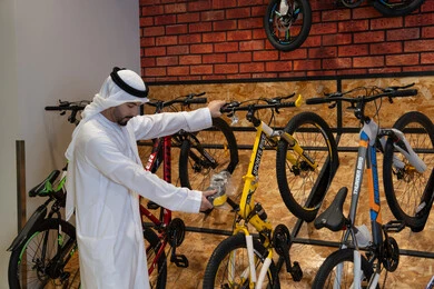 رجل إماراتي باللباس التقليدي يتسوق لشراء دراجة هوائية