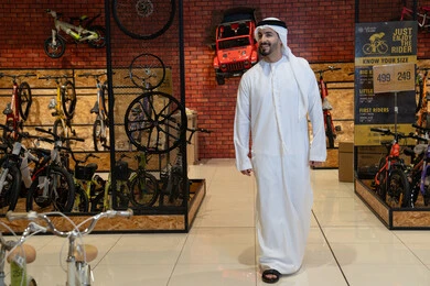 رجل إماراتي بالكندورة التقليدية في معرض دراجات هوائية