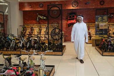 رجل إماراتي بالكندورة التقليدية في معرض دراجات