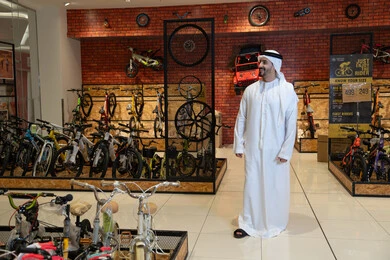 رجل إماراتي بالزي التقليدي في متجر دراجات