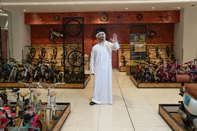 رجل إماراتي بالكندورة داخل متجر دراجات هوائية