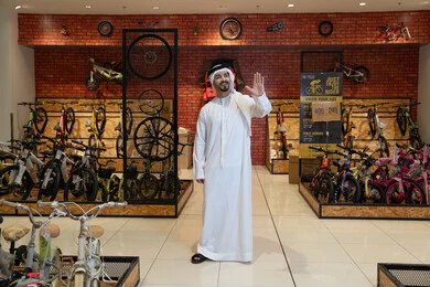 رجل إماراتي بالكندورة داخل متجر دراجات هوائية